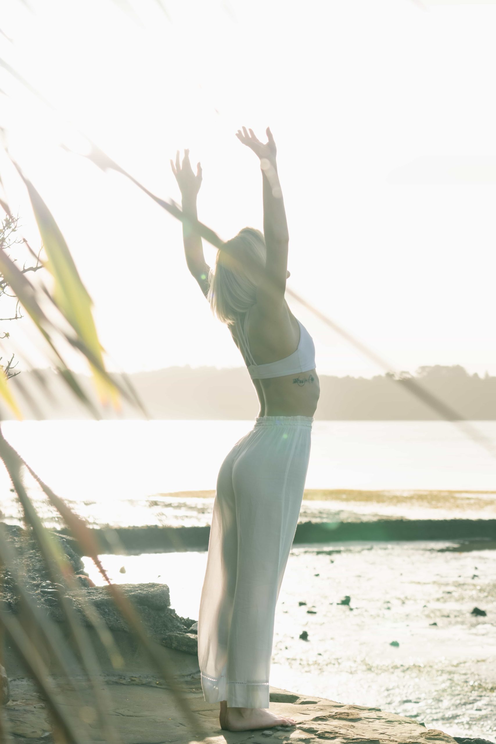 This image portrays a girl nourishing her spirituality by practicing yoga on a beach.